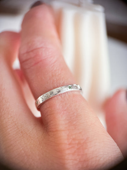 Anello artigianale Aurora Bariletti in argento 925, inciso a mano con margherite e zaffiri verdi dello Sri Lanka.