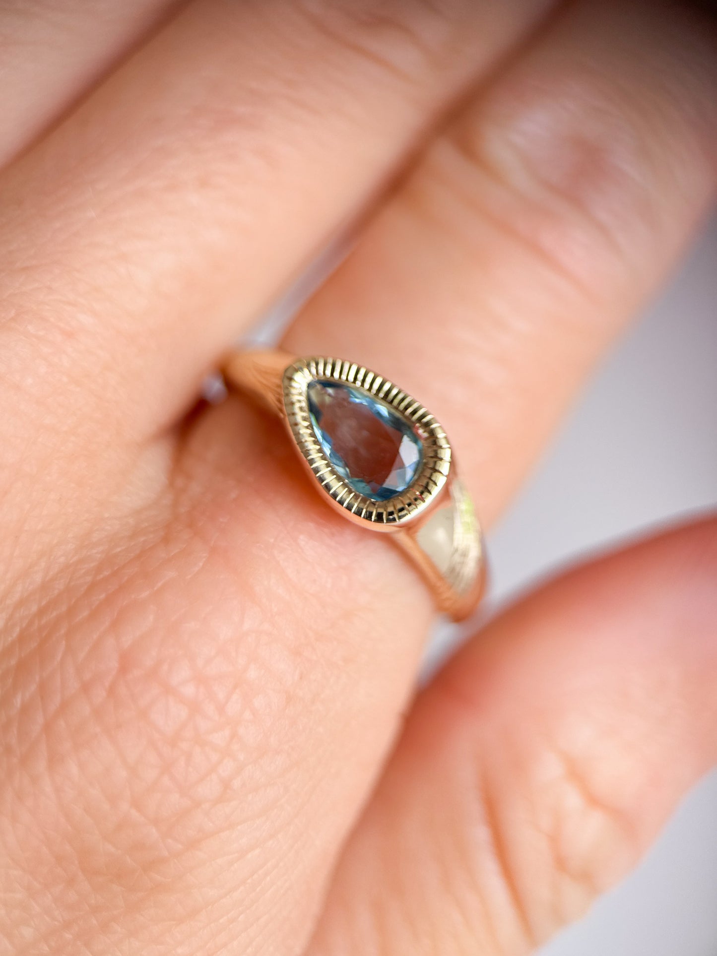 Anello indossato in oro giallo 9kt e acquamarina taglio a goccia con incisioni luminose fatte a mano. Gioiello esclusivo creato da Aurora Bariletti nel suo laboratorio a riva del garda, italia.