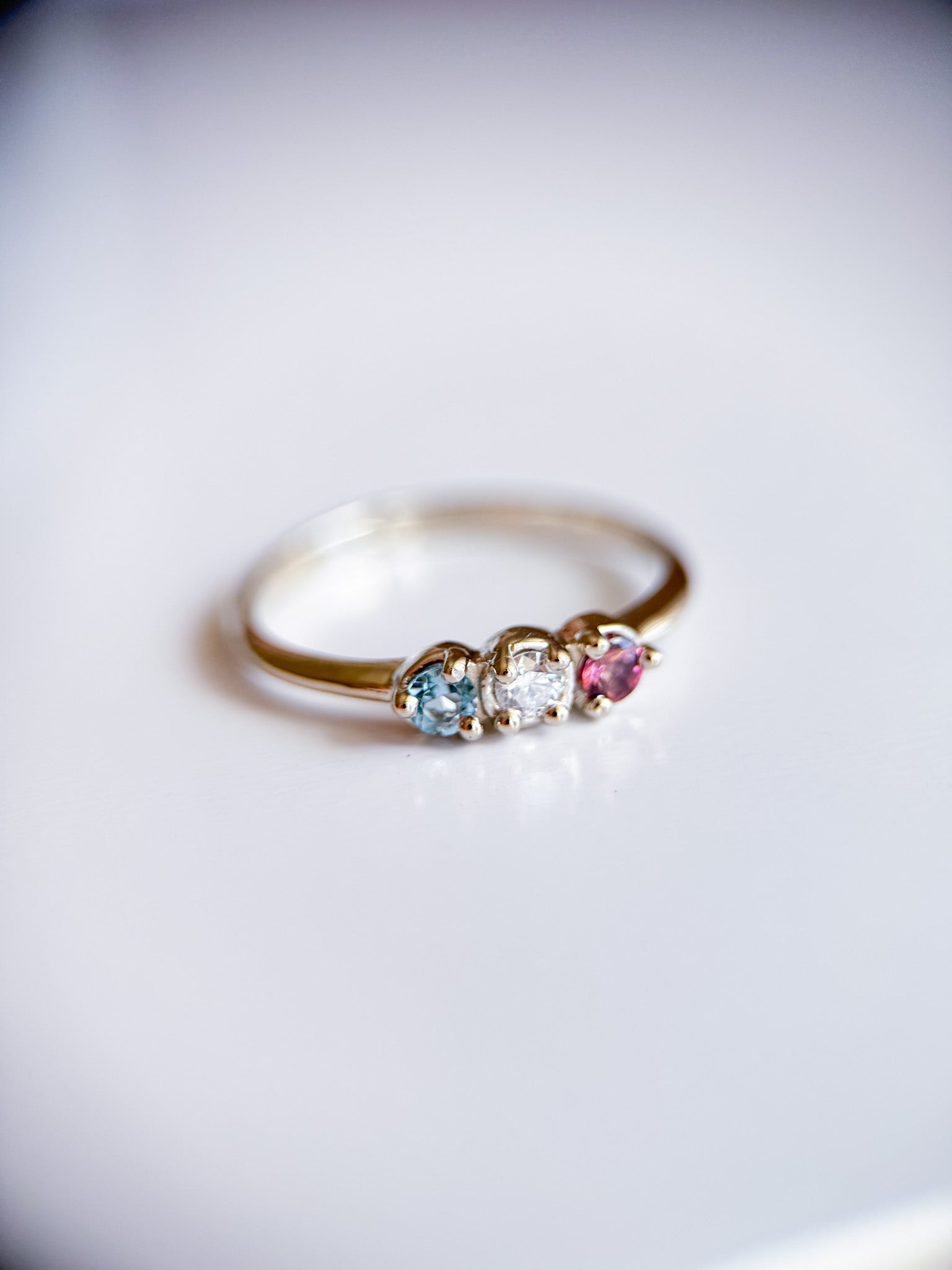 Anello fidanzamento trilogy in oro su misura da Aurora Bariletti con pietre che simboleggiano i membri della famiglia. Gioiello artigianale creato nel laboratorio orafo di Riva del Garda.