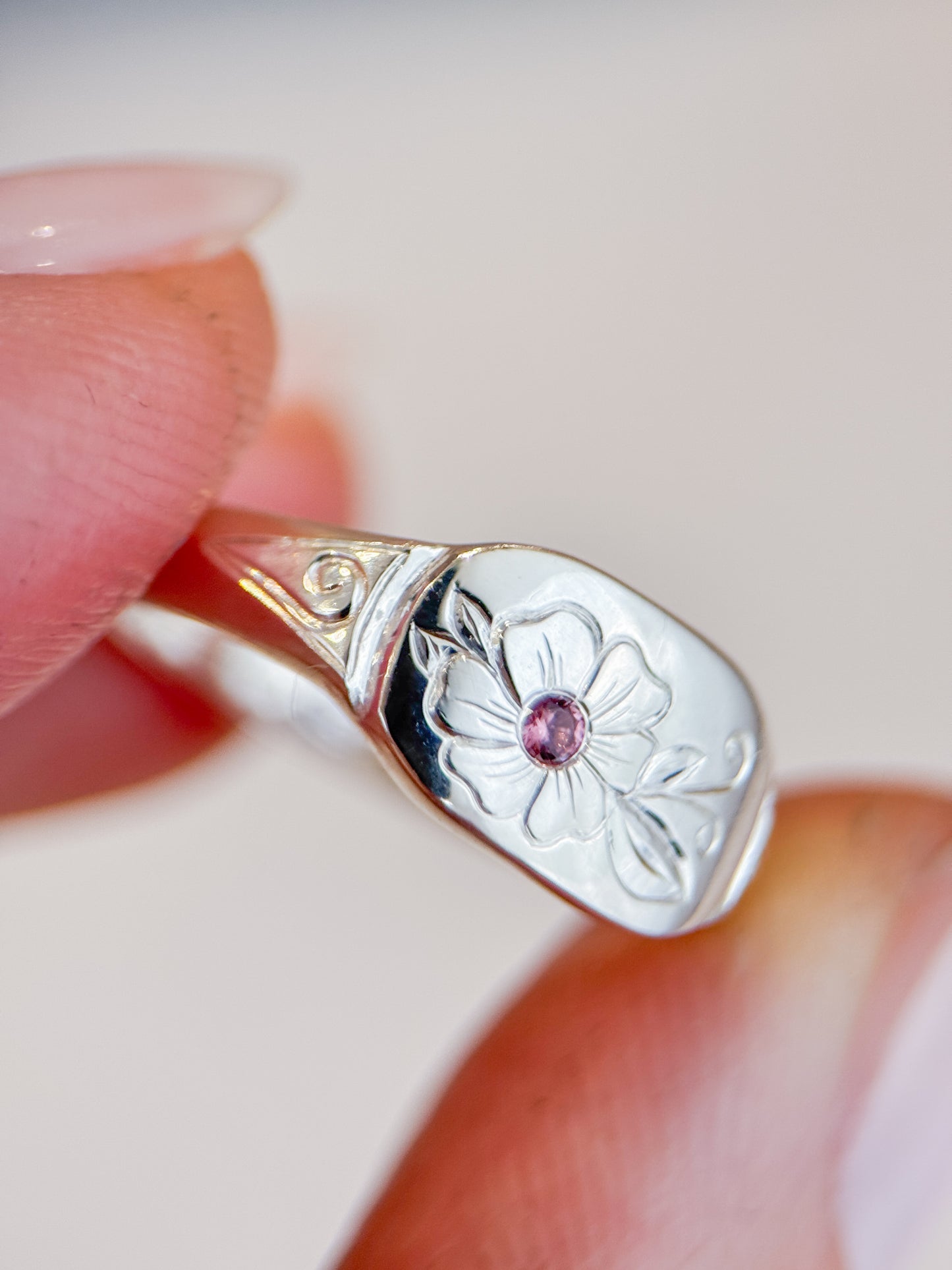 Anello artigianale esclusivo in argento 925, inciso a mano con un fiore centrale che accoglie una tormalina rosa. Creato con cura nel laboratorio di Aurora Bariletti.