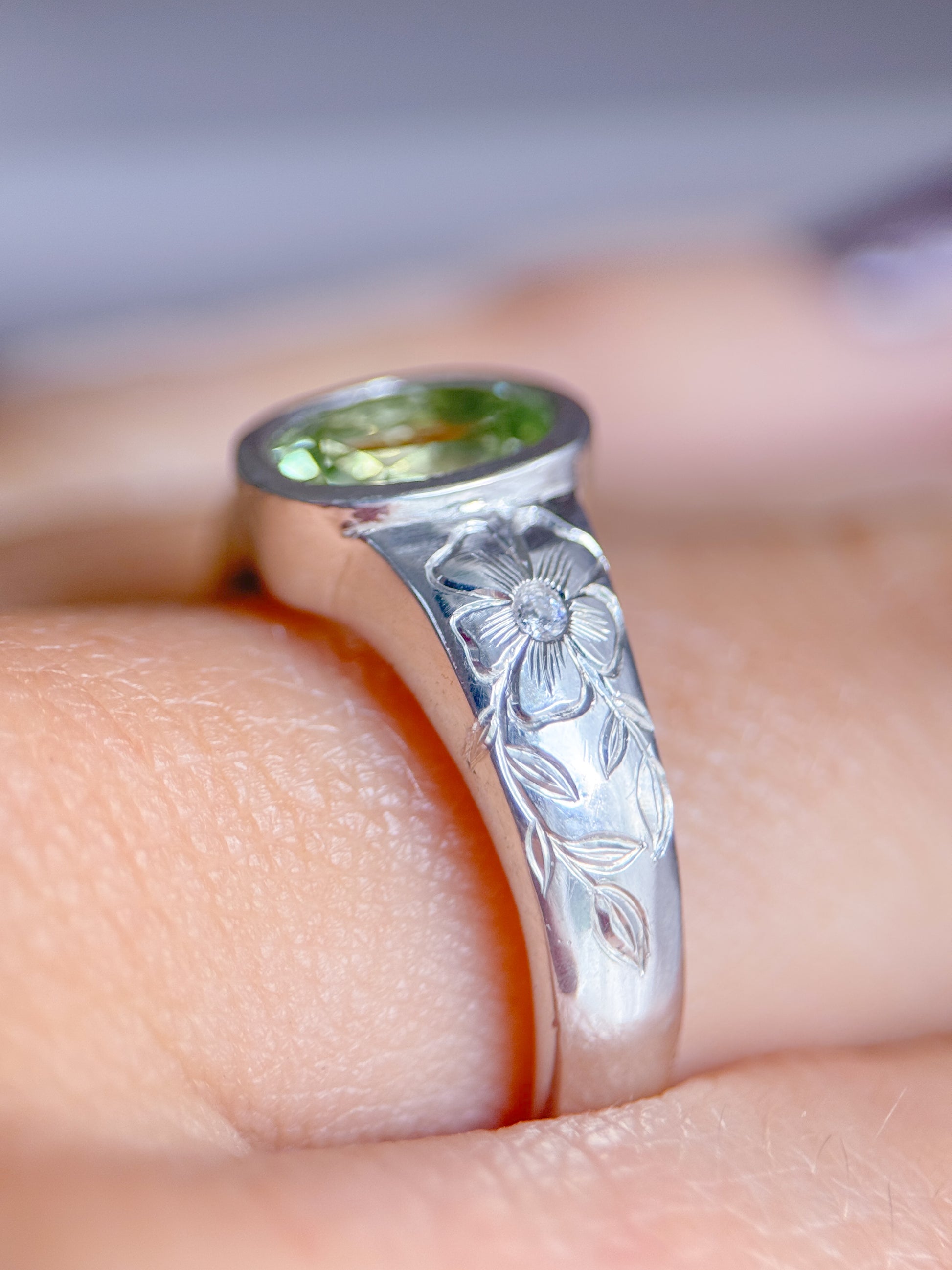 Anello indossato in argento 925 con tormalina verde ovale e incisioni floreali eseguite a mano sul gambo. Realizzato da Aurora Bariletti nel suo laboratorio a riva del garda, italia.