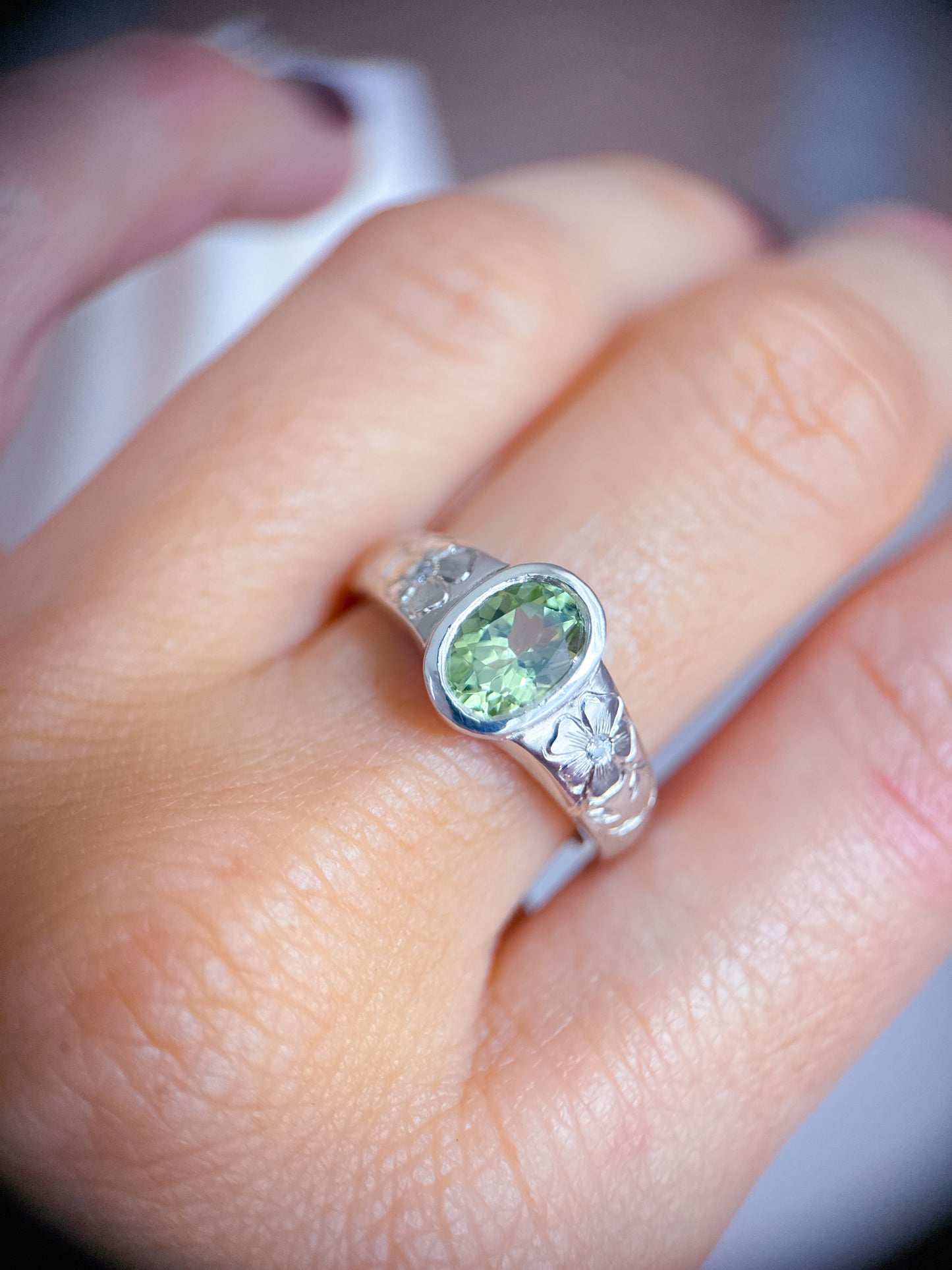 Anello indossato in argento 925 con tormalina verde ovale e incisioni floreali eseguite a mano sul gambo. Realizzato da Aurora Bariletti nel suo laboratorio a riva del garda, italia.