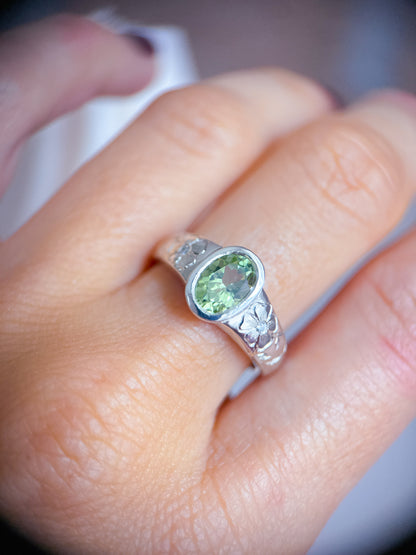 Anello indossato in argento 925 con tormalina verde ovale e incisioni floreali eseguite a mano sul gambo. Realizzato da Aurora Bariletti nel suo laboratorio a riva del garda, italia.