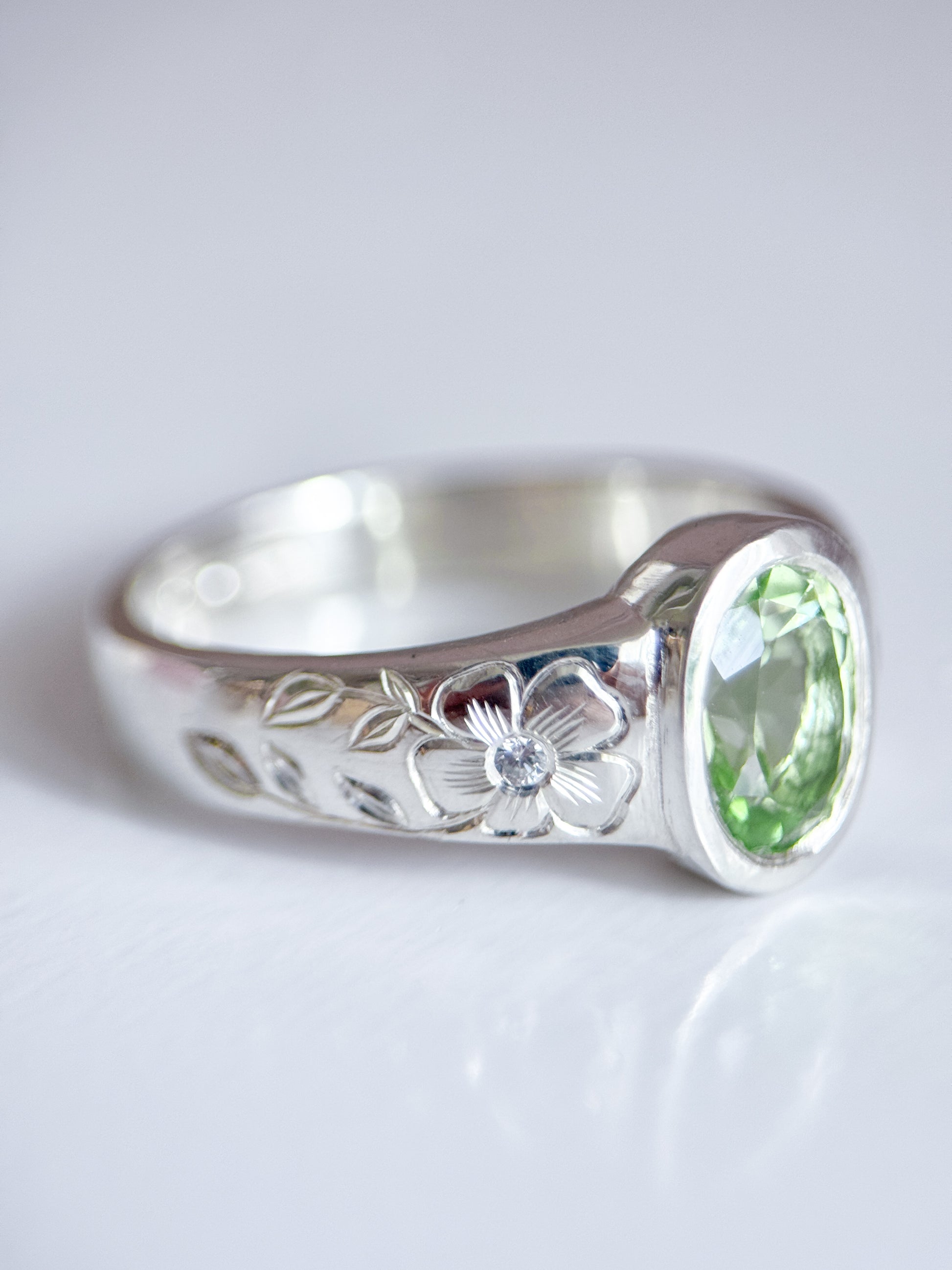 Anello in argento 925 con tormalina verde ovale e incisioni floreali eseguite a mano sul gambo. Realizzato da Aurora Bariletti nel suo laboratorio a riva del garda, italia.