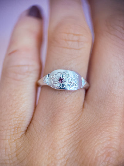 Anello artigianale esclusivo in argento 925 con tormalina rosa, indossato sulla mano. La vista ravvicinata mostra il fiore inciso a mano e i suoi dettagli realizzati da Aurora Bariletti.