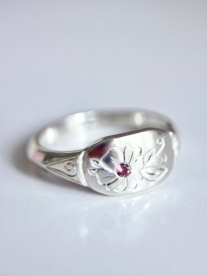 Anello artigianale esclusivo in argento 925, inciso a mano con un fiore centrale che accoglie una tormalina rosa. Creato con cura nel laboratorio di Aurora Bariletti.