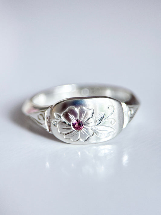 Anello artigianale esclusivo in argento 925, inciso a mano con un fiore centrale che accoglie una tormalina rosa. Creato con cura nel laboratorio di Aurora Bariletti.