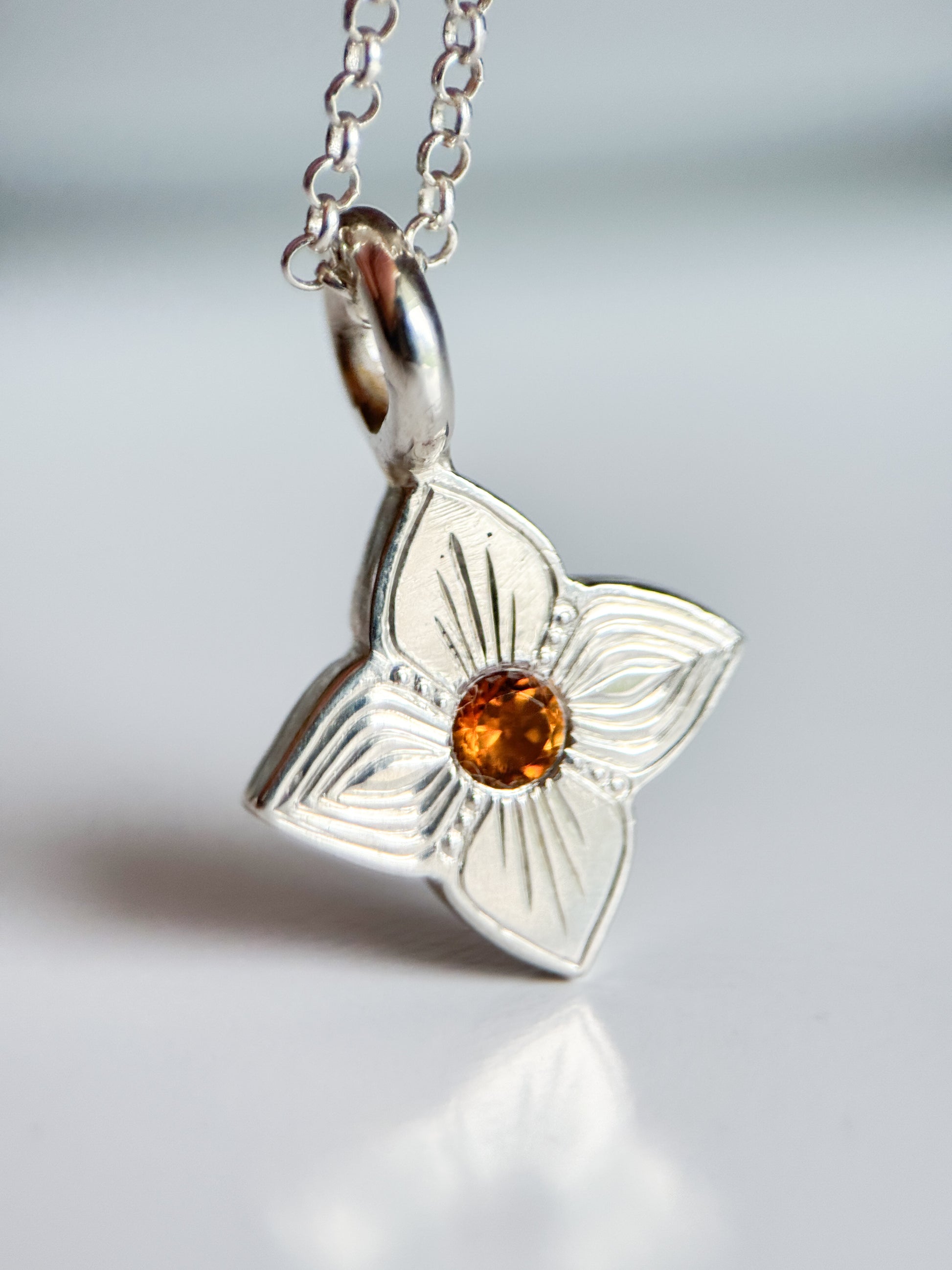 Pendente realizzato a mano libera da Aurora Bariletti, con quarzo citrino al centro. I tagli obliqui sui petali giocano con la luce, creando un piccolo gioiello luminoso e unico.