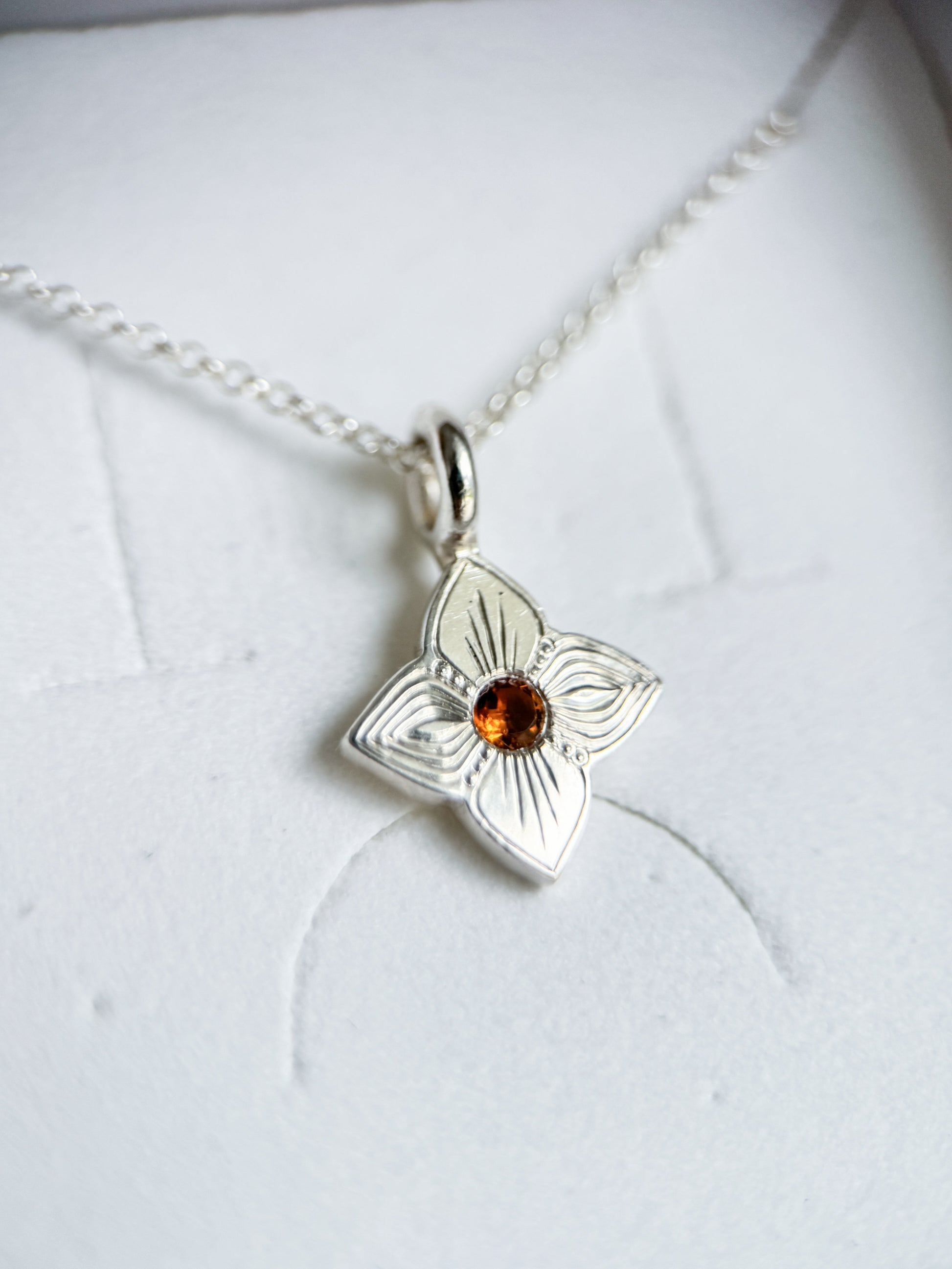 Pendente realizzato a mano libera da Aurora Bariletti, con quarzo citrino al centro. I tagli obliqui sui petali giocano con la luce, creando un piccolo gioiello luminoso e unico.