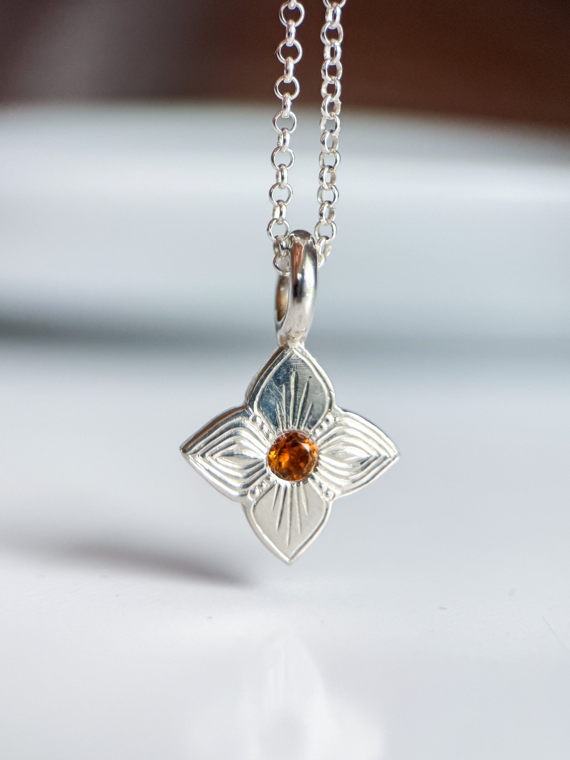 Pendente realizzato a mano libera da Aurora Bariletti, con quarzo citrino al centro. I tagli obliqui sui petali giocano con la luce, creando un piccolo gioiello luminoso e unico.