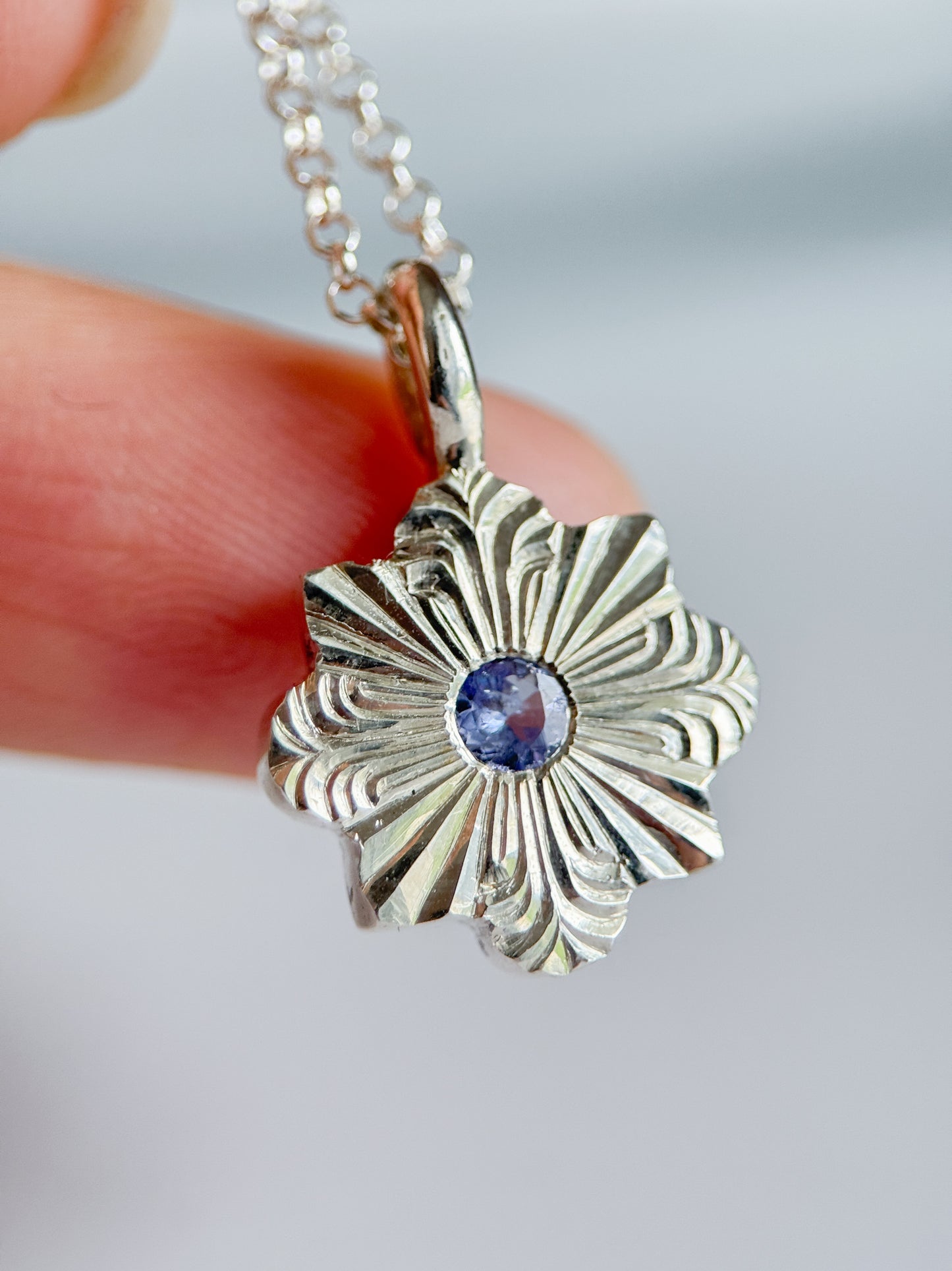 Pendente inciso a mano libera da Aurora Bariletti, con tanzanite al centro. I tagli dritti e curvi evocano la forma di un fiocco di neve.