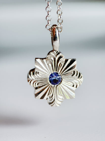 Pendente inciso a mano libera da Aurora Bariletti, con tanzanite al centro. I tagli dritti e curvi evocano la forma di un fiocco di neve.