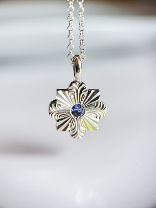 Pendente inciso a mano libera da Aurora Bariletti, con tanzanite al centro. I tagli dritti e curvi evocano la forma di un fiocco di neve.