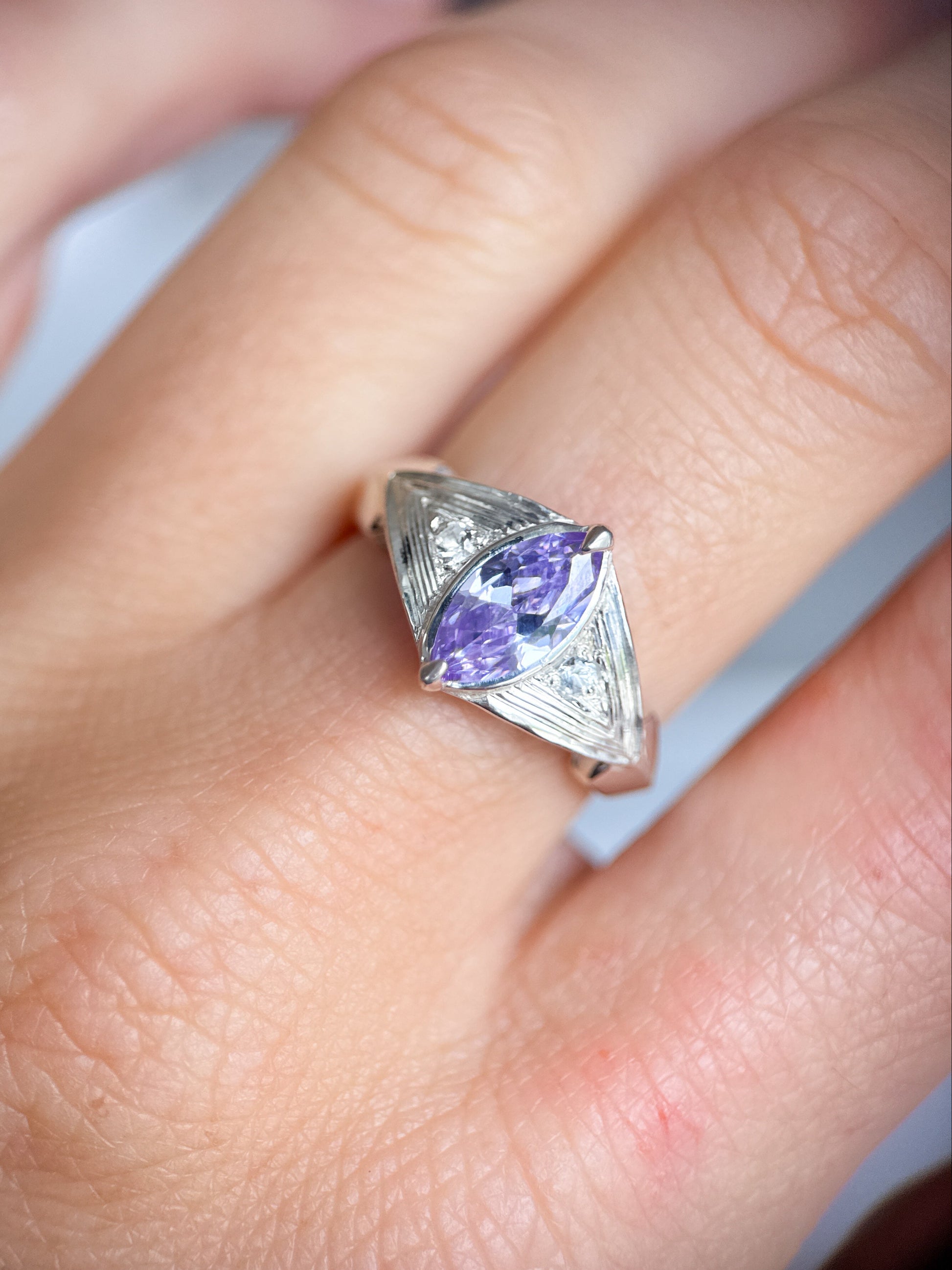 Indossato, questo anello di Aurora Bariletti mostra tutto il suo splendore: le incisioni a mano e l’ametista marquise riflettono la luce naturale, creando un delicato gioco di luci sulla pelle