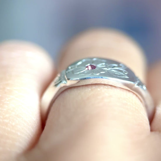 Video anello indossato in argento 925, inciso a mano con un fiore centrale che accoglie una tormalina rosa. Creato con cura nel laboratorio di Aurora Bariletti.