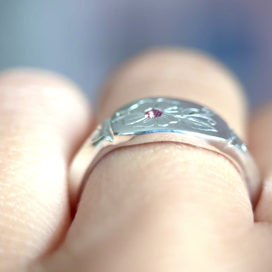 Video anello indossato in argento 925, inciso a mano con un fiore centrale che accoglie una tormalina rosa. Creato con cura nel laboratorio di Aurora Bariletti.